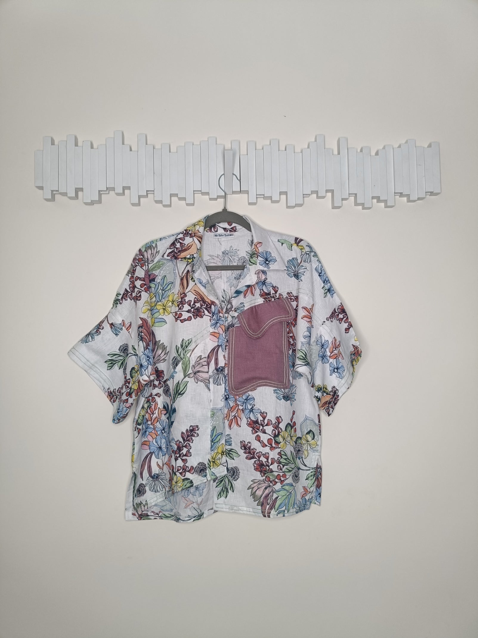 Floral patterned shirt on a hanger against a plain background